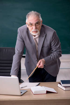 Old male teacher in front of blackboardの写真素材