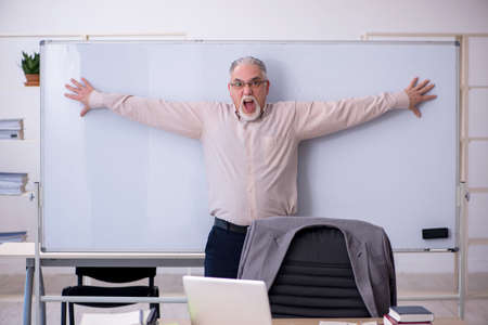 Old male teacher in front of whiteboardの写真素材