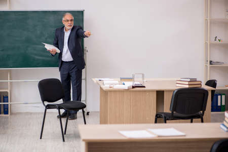Old male teacher in front of blackboardの写真素材