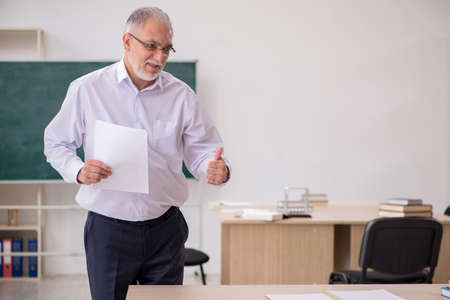 Old male teacher in front of blackboardの写真素材
