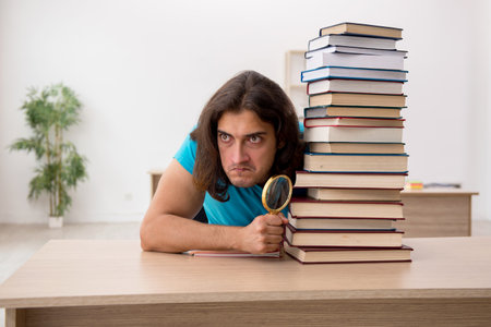 Young male student and a lot of books in the classの写真素材