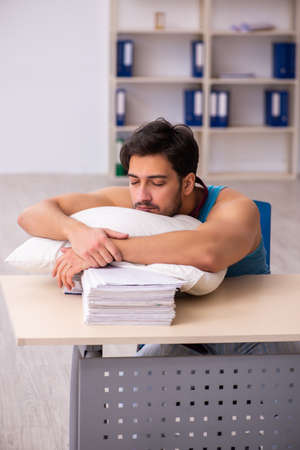 Young male employee coming to work straight from bedの写真素材