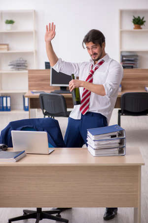 Young alcohol addicted male employee working in the officeの写真素材