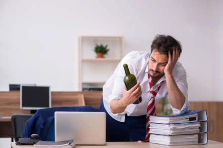 Young alcohol addicted male employee working in the officeの写真素材