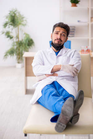 Tired young male doctor lying on the couch at the hospitalの写真素材