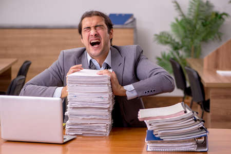 Young male employee and too much work in the office