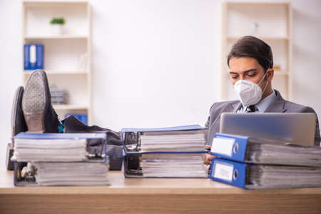 Young male employee working at workplace during pandemicの写真素材