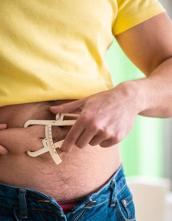 Young man measuring body fat with calipersの写真素材