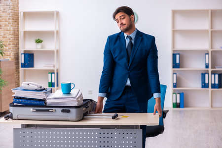 Young male employee preparing for business trip at workplaceの写真素材