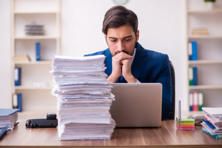 Young businessman employee unhappy with excessive work in the officeの写真素材