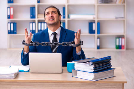 Chained male employee unhappy with excessive work in the ofiiceの写真素材