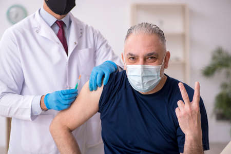 Old male patient visiting young male doctor in vaccination conceptの写真素材