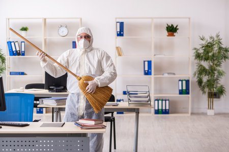 Old male contractor cleaning the office holding broomの写真素材