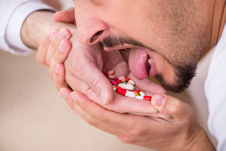 Old male doctor suggesting pills to young male patientの写真素材