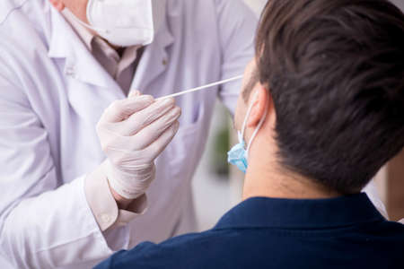 Young male patient visiting old male doctor during pandemicの写真素材
