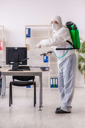 Old male contractor in office disinfection conceptの写真素材