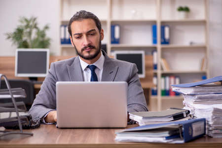 Young businessman employee unhappy with excessive work in the ofの写真素材