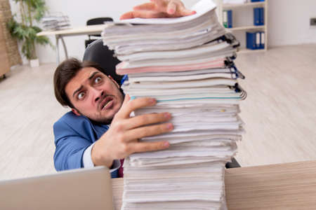 Young male employee and too much work in the office