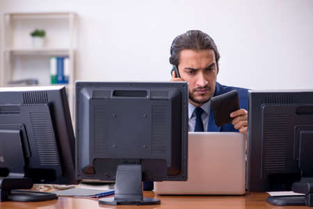 Young male employee in multitasking concept