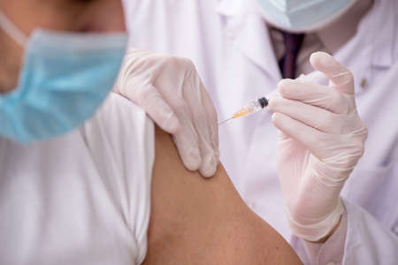 Young male patient visiting old male doctor in vaccination conceの写真素材