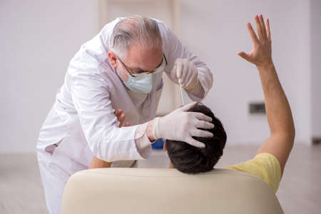 Young male patient visiting old male doctor otorhinolaryngologisの写真素材