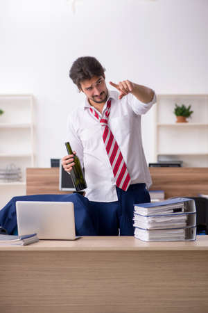 Young alcohol addicted male employee working in the officeの写真素材