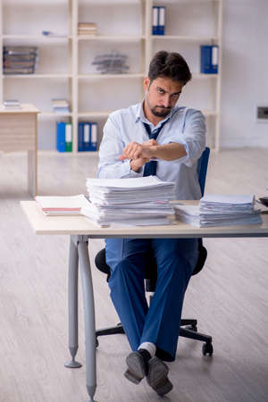 Young male employee unhappy with excessive work in the officeの写真素材