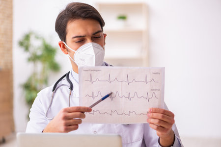 Young male doctor cardiologist working in the clinic during pandの写真素材