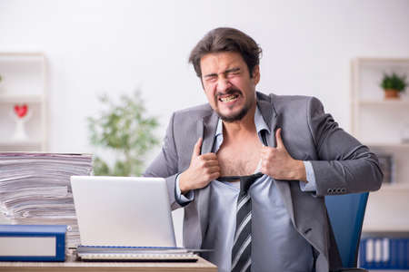 Young male employee and too much work in the officeの写真素材