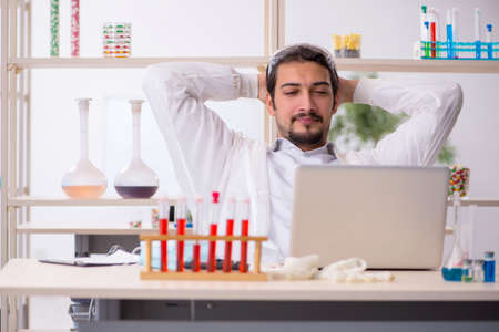 Young male chemist sitting at computer at the labの写真素材