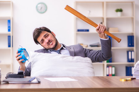 Young male employee in oversleeping conceptの写真素材