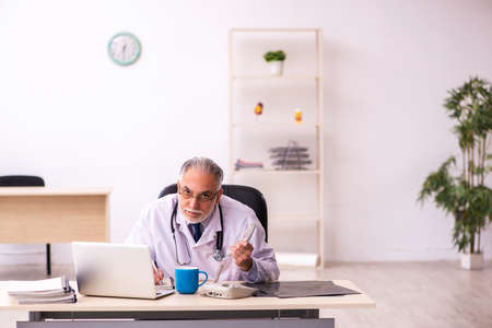 Aged male doctor working in the clinic