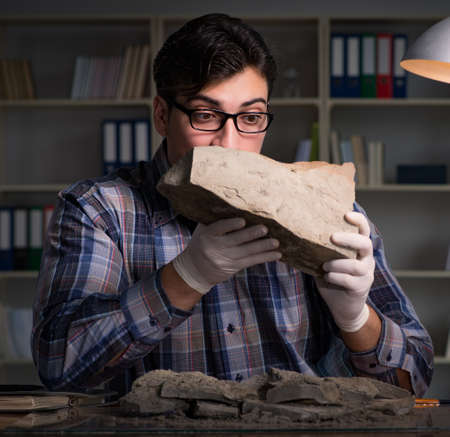 Archeologist working late night in officeの写真素材