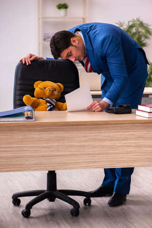 Young male employee and his toy bear boss in funny conceptの写真素材