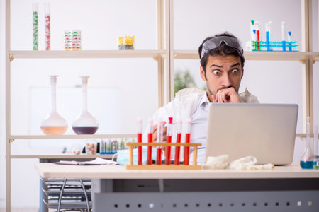 Young male chemist sitting at computer at the labの写真素材