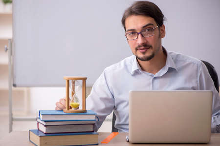 Young male teacher in time management concept