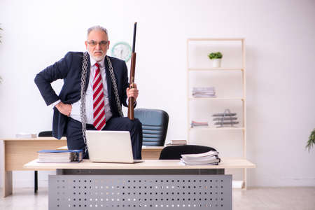 Old businessman employee holding riffle in the officeの写真素材