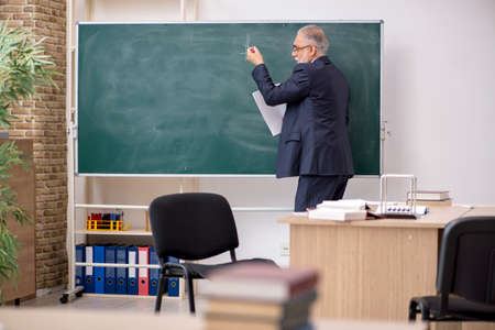 Old male teacher in front of blackboardの写真素材