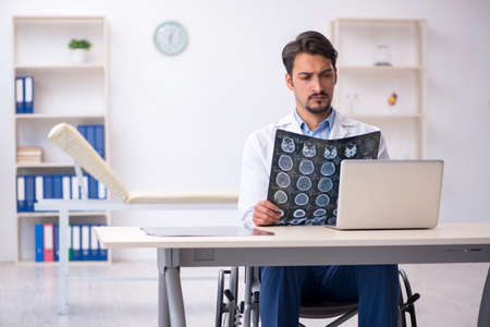 Young male doctor in wheel-chair working in the clinic
