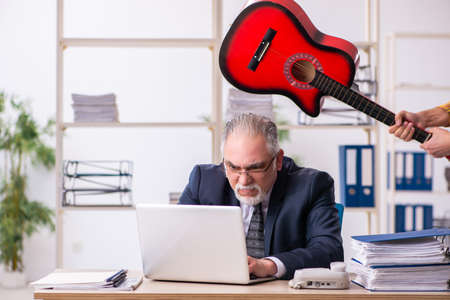 Old male employee unhappy with excessive work in the officeの写真素材