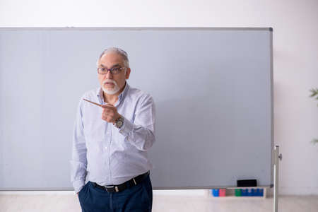 Old male teacher in front of whiteboardの写真素材
