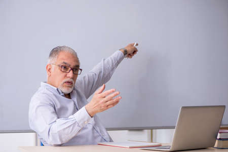 Old male teacher in front of whiteboard