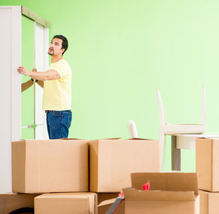 Young handsome man moving in to new house with boxes