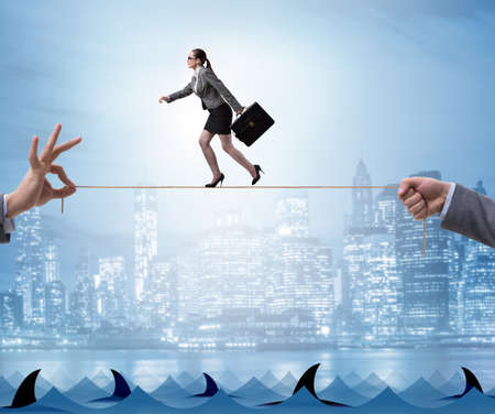 Businesswoman walking on tight rop in business conceptの写真素材