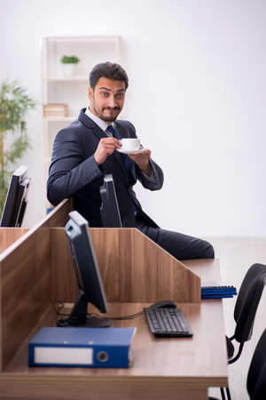 Young male employee drinking coffee during breakの写真素材