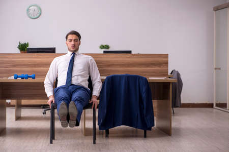 Young businessman employee doing sport exercises at workplaceの写真素材