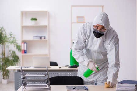 Young male contractor disinfecting office during pandemicの写真素材