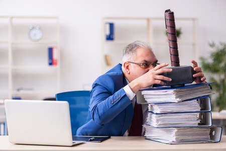 Old male employee unhappy with too much work in the officeの写真素材
