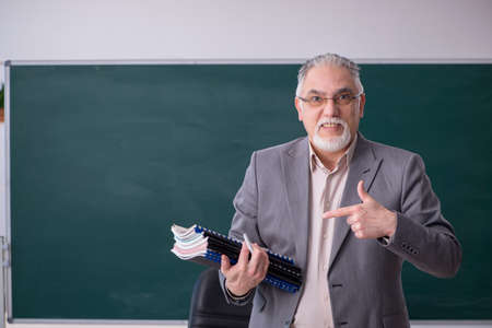 Old male teacher in front of blackboardの写真素材