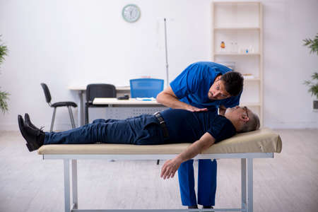 Old man visiting young male doctorの写真素材